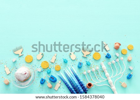 religion image of jewish holiday Hanukkah with menorah (traditional candelabra), spinning top and doughnut over wooden background