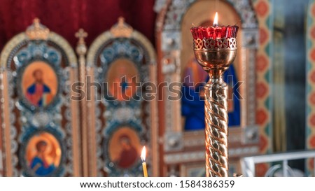 Orthodox Church Lamp with lit Candle and Red Glass on the icon background.