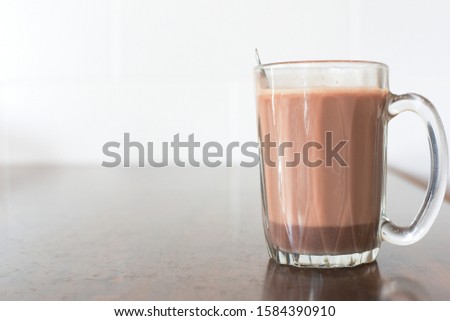 Hot chocolate in old vintage glass with spoon on wooden table, morning drink 
