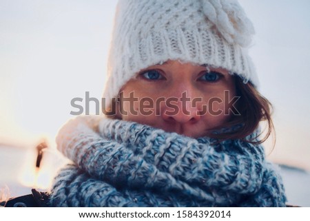 A red nosed Scandinavian woman all bundled up for skiing season in winter. Back lit picture, with low winter sun.