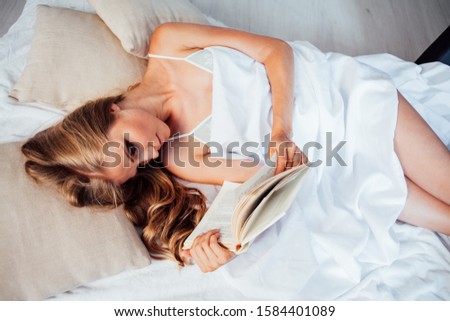 portrait of a beautiful blonde woman reading a book before going to bed