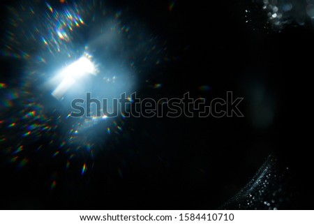 Light over black background. Easy to add overlay or screen filter over photos. Abstract sun burst with digital lens flare background. Gleams rounded and hexagonal shapes, rainbow halo.