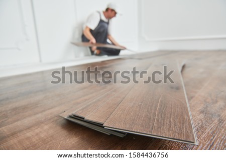 worker laying vinyl floor covering at home renovation Royalty-Free Stock Photo #1584436756