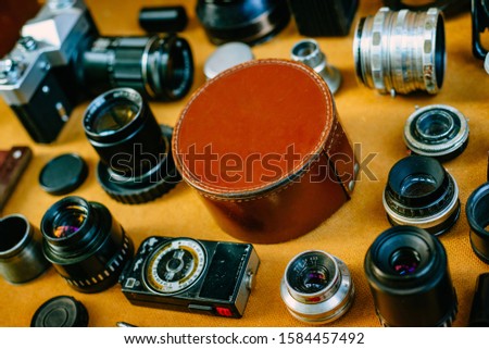 Closeup retro mockup, round leather vintage box in center and vintage photographic accessories and quipments around on wooden background. Side view