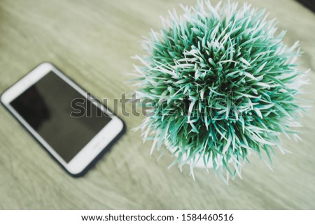 Fake trees and white cell phones on wooden floors, top view