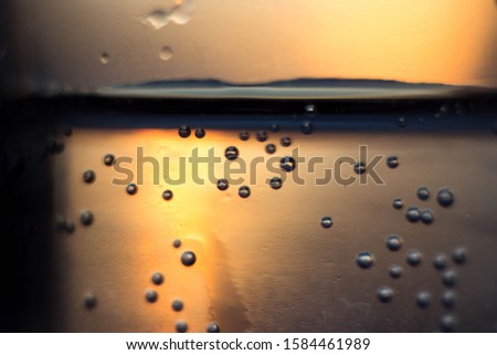 Bubbles in a glass at sunset. Gas bubbles in a glass beaker illuminated from behind by the setting sun