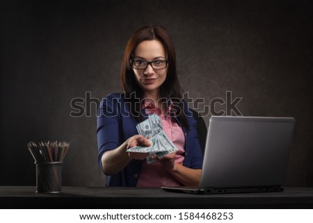 Successful businesswoman at the table on a dark background with laptop and money. Bank Sales Manager
