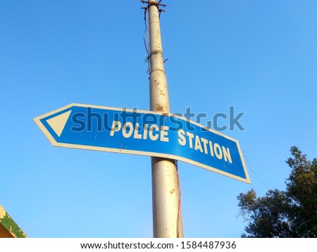 A blue colored, police station direction sign on pole