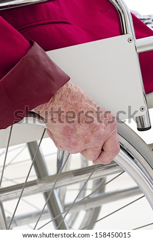 Hand placed on the wheel of a wheelchair - symbol picture of disability