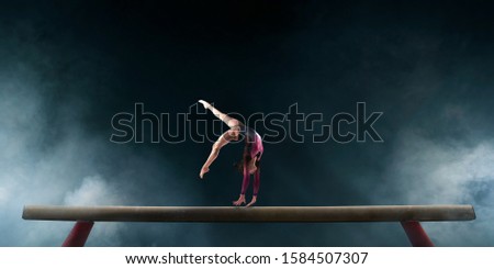 Female gymnast doing a complicated trick on gymnastics balance beam. Royalty-Free Stock Photo #1584507307