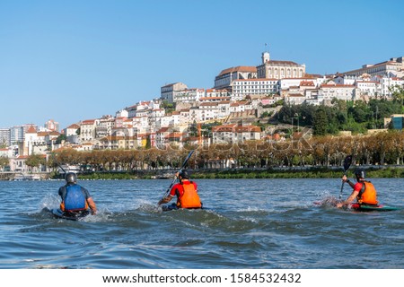 Three men in canoes exercising on Mondego river in Coimbra, Portugal Royalty-Free Stock Photo #1584532432