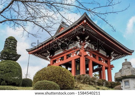 Red Japanese architecture in daylight with cherry blossom (Sakura) branch.