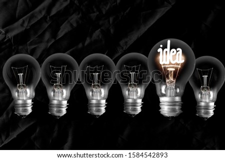 Group of dimmed light bulbs and shining one of them with fiber in Idea shape isolated on black background.