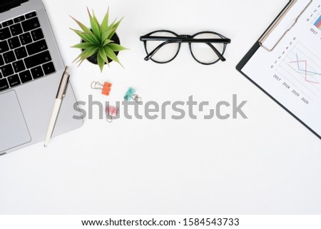 Flat lay business finance office concept on white table desk with Laptop computer and graph document, supplies, Top view with copy space
