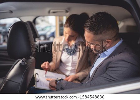 Beautiful young couple is choosing a new car at dealership