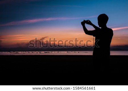 The silhouette of a man shooting the sea with a mobile phone