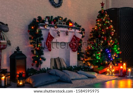 Christmas decorated fireplace with socks next to the Christmas tree, gifts, toys and garland lights