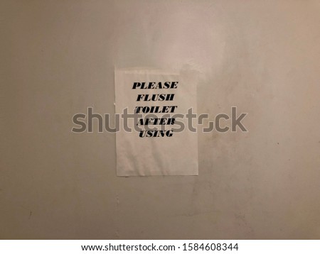 “Please Flush Toilet After Using” sign on the wall.