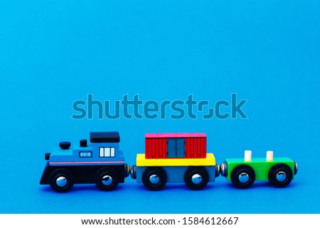 Colourful wooden toy train on blue background with copy space