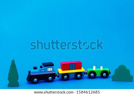 Colourful wooden toy train on blue background with copy space