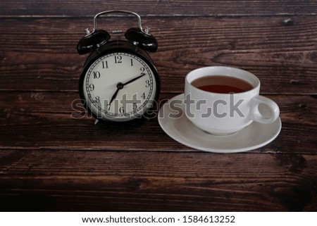 vintage alarm clock with a cup of tea