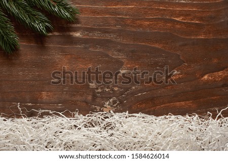 Branch of spruce and imitation of snow made of paper on a vintage wooden background.