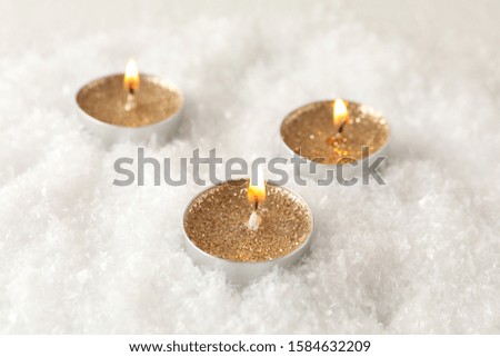 Candles with glitter on snow background, close up