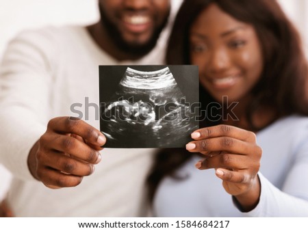 Happy to be parents. African couple demonstrating sonogram picture, cropped