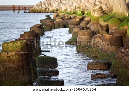 The seawall around the sea port facilities is made of concrete tetrapods (traveling-wave protection), rubble-mound breakwater Royalty-Free Stock Photo #1584693154