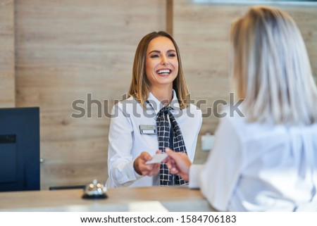 Receptionist and businesswoman at hotel front desk Royalty-Free Stock Photo #1584706183