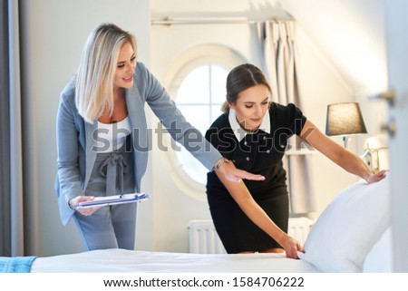 Adult chambermaid and hotel manager cleaning the room Royalty-Free Stock Photo #1584706222