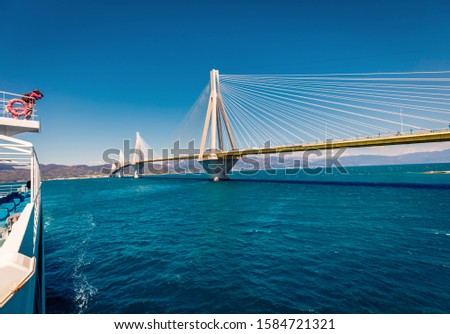 Photographer takes picture of Rion-Antirion Bridge from ferryboat. Splendid summer view of Gulf of Corinth, Greece, Europe. Amazing Mediterranean seascape. Traveling concept background.