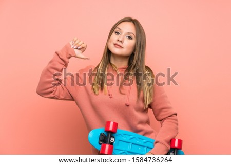 Teenager girl with skate over isolated pink background