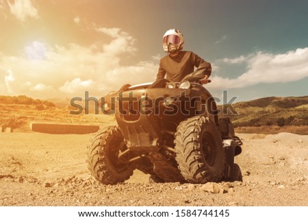 A man is driving ATV on off-road. Sunny.