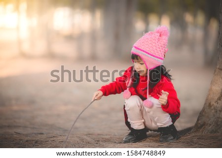 Portrait of cute asian little girl wear Winter clothes at the forest of the park,Thailand people pose for take a picture,Happy time