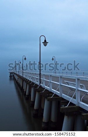 Sunrise on the pier at the seaside. Foggy autumn morning on the sea Gdynia Orlowo, Poland. Long exposure photography 