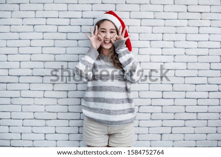 Portrait cute Asian young woman in costume Christmas and wear red santa claus hat with smile on white brick background and copy space. Happy of teen woman in theme Christmas.