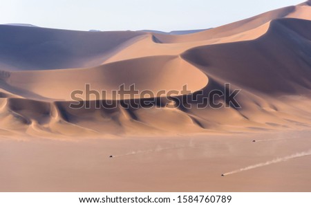 Huge dunes of the desert. the cars passing by a huge sand dunes in dasht e lut or sahara desert.  Fine place for photographers and travelers. Beautiful structures of sandy barkhans.
