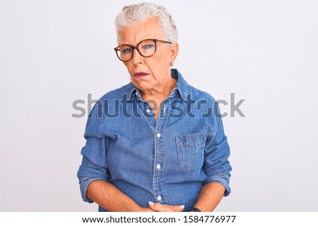 Senior grey-haired woman wearing denim shirt and glasses over isolated white background looking sleepy and tired, exhausted for fatigue and hangover, lazy eyes in the morning.