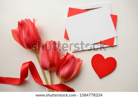 valentine's day concept. bouquet of red tulips, red wooden heart and an envelope on a white background. place for text. flat lay. top view