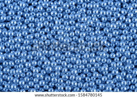 Candy sugar pearls, cake decoration, copy space. Small silver sparkle balls texture. Classic blue background. Color of the year 2020. Top view, flat lay