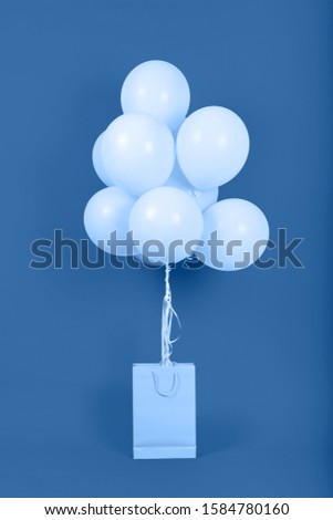 Classic blue background with bunch of flying balloons in paper shopping bag, copy space. Color of the year 2020. Christmas, birthday, valentine, wedding, holiday concept