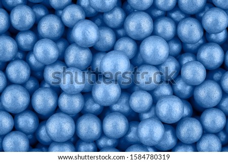 Candy sugar pearls, cake decoration, copy space. Small silver sparkle balls texture. Classic blue background. Color of the year 2020. Top view, flat lay