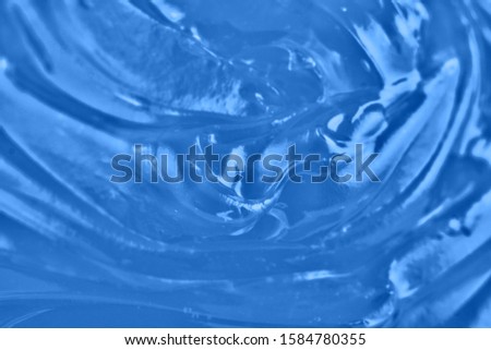 Classic blue background. Color of the year 2020. Top view, flat lay. Gelatin jelly texture, copy space. Squeezed transparent cosmetic gel