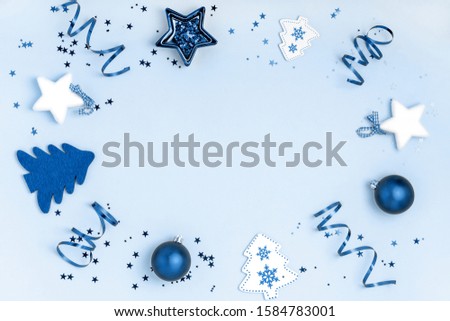 New Year and Christmas composition. Frame from balls, stars, chrismas tree on blue background. Top view, flat lay, copy space. Trendy color of the year 2020. Royalty-Free Stock Photo #1584783001