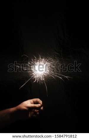 Hand with sparkler on dark background. Celebrating new year with sparkler. Hand holding sparkler on dark background. Christmas fun. New year concept.