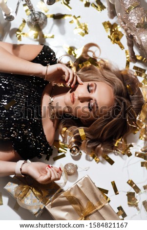 Happy New Year 2020. Beautiful girl with closed makeup eyes. Close up photo of positive girl lie on floor in house with Christmas comfort atmosphere indoors. Garlands, gifts, Christmas tree. 