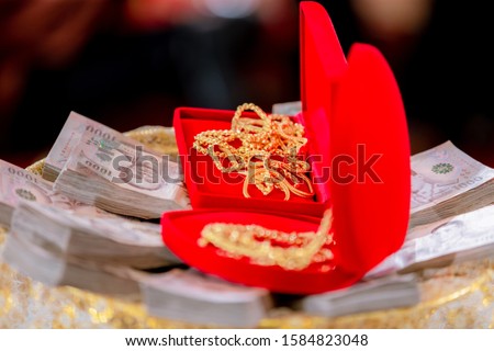 Focus bride price in Thai wedding ceremony, gold necklace, thai banknote and wedding rings. Asian Wedding Traditions. image for background, copy space and objects.
