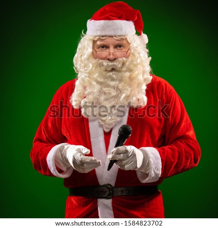 Santa Claus holds a microphone in his hands, sings and poses on a dark red background