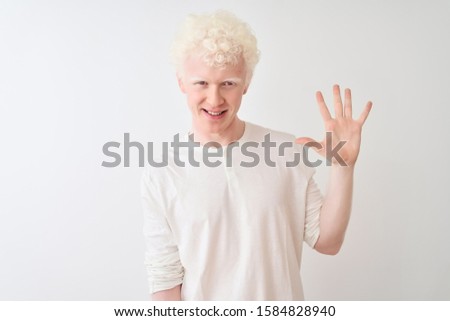 Young albino blond man wearing casual t-shirt standing over isolated white background showing and pointing up with fingers number five while smiling confident and happy.
